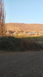 a field with a group of buildings in the background at Casa de campo in Colina +3 photos