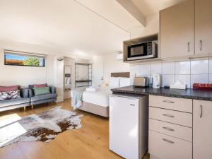 a kitchen and living room with a bed and a microwave at Aqua Sands #1 - Stay Waiheke in Oneroa