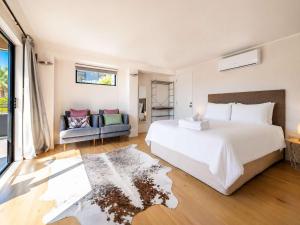 a bedroom with a large white bed and a couch at Aqua Sands #1 - Stay Waiheke in Oneroa