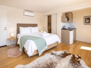 a bedroom with a large white bed and a kitchen at Aqua Sands #1 - Stay Waiheke in Oneroa