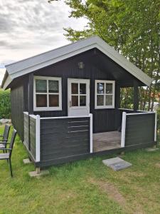 a black tiny house with a porch and a bench at Vrensted Hostel B&B in Løkken
