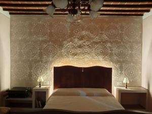 a bedroom with a bed and a wall with a damask wallpaper at I leoni di Montecchio in Castiglion Fiorentino