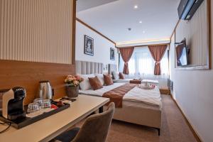 a hotel room with a bed and a table at Vila Hera Spa in Vrbas