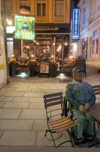 a man sitting on a bench in front of a building at Apartment nad Sveikem in Karlovy Vary