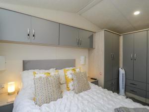a bedroom with a white bed with pillows and cabinets at The Cotswold Holiday Lodge in Evesham