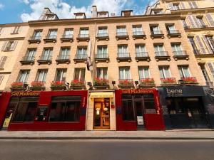 a building with red doors and windows on a street at Hôtel La Sanguine in Paris