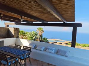 a patio with a bench and a table and chairs at DAMMUSI IL CARRUBO in Pantelleria