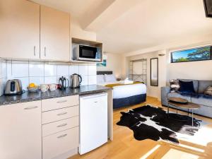 a kitchen and a living room with a bed at Aqua Sands #2 - Stay Waiheke in Oneroa