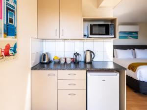 a kitchen with a microwave and a bed in a room at Aqua Sands #2 - Stay Waiheke in Oneroa