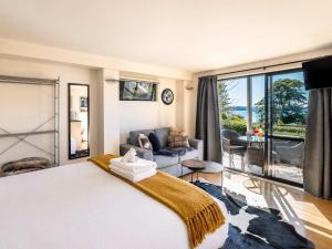 a bedroom with a large bed and a living room at Aqua Sands #2 - Stay Waiheke in Oneroa