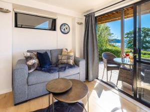 a living room with a couch and a table at Aqua Sands #2 - Stay Waiheke in Oneroa