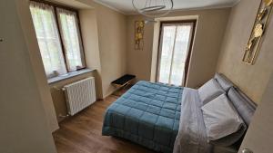 ein Schlafzimmer mit einem blauen Bett und zwei Fenstern in der Unterkunft La Ràndula in Balme