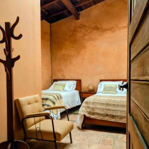 a bedroom with two beds and a chair in it at Casa Orígenes Hotel Boutique in Pamplona
