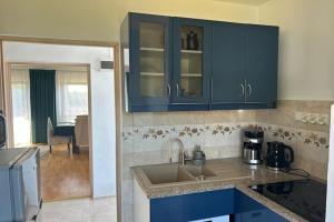 a kitchen with blue cabinets and a kitchen sink at Apartment in Dabrowa near the Sea in Gostyniec