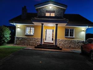 a small yellow house with a stone wall at VV Las Picarolas in Muros de Nalón
