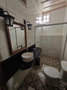 a bathroom with a sink and a toilet and a mirror at CASA RAIZ cama café e prosa in Ouro Preto