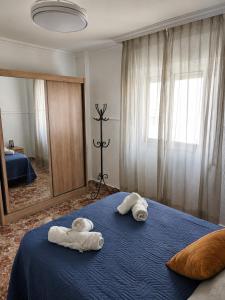 a bedroom with towels on a blue bed with a mirror at Apartamento EL LUCENTINO in Lucena