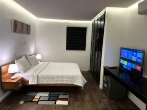 a bedroom with a bed and a flat screen tv at Melroseplace Complex in Bonabéri