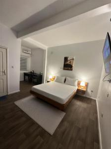 a white bedroom with a bed and a desk at Melroseplace Complex in Bonabéri