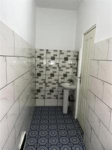 a white bathroom with a sink and a toilet at Melroseplace Complex in Bonabéri