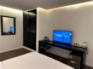 a bedroom with a bed and a desk with a television at Melroseplace Complex in Bonabéri