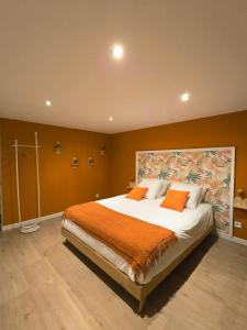 a bedroom with a large bed with an orange blanket at La Parenthèse du Buisson Bailly - Jacuzzi, Détente et Bien être près de Provins in Choisy-en-Brie +13 photos