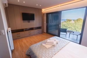 a bedroom with a bed with a television and a balcony at CASA UNO Horizon in Platamonas
