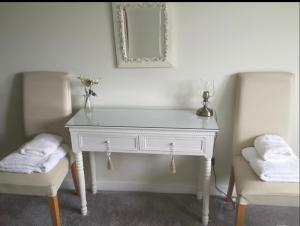 a white desk with two chairs and a mirror at Lomond Villa in Balloch
