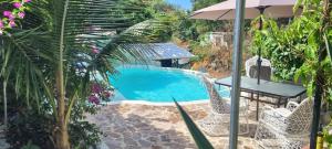 ein Schwimmbecken mit zwei Stühlen und einem Sonnenschirm in der Unterkunft Meridiana in Las Terrenas