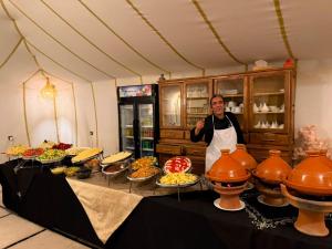 a man standing in front of a buffet of food at Hidden luxury Camp in Merzouga