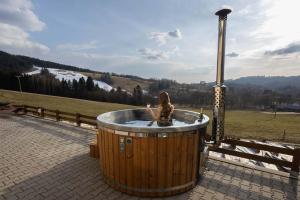 a woman sitting in a hot tub in a field at Chalupa Šťastný kopec in Deštné v Orlických horách
