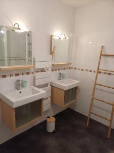 a bathroom with two sinks and a ladder and mirrors at Betty in Saint-Gaudens