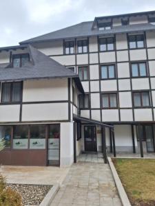 a white and black building with a driveway at Apartman Glorija in Brzeće +4 photos