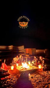 a group of people sitting around a fire pit at night at SEVEN PILLARS lUXURY CAMP in Wadi Rum