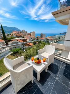 a balcony with two chairs and a table with fruit on it at becici residance with pool & sauna in Budva