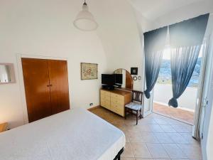 a bedroom with a bed and a television and a window at PELAGOS - Agenzia Immobilevante in Ponza