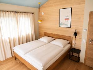 a bedroom with a large bed with white sheets at Das Kofelau in Oberammergau