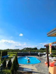 a person swimming in a pool in a backyard at Apartamenty Wilga - spokojne miejsce z ciszą nocną od 22, całorocznym zewnętrznym wspólnym jacuzzi, sauną i wakacyjnym basenem in Wilga