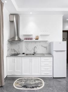 a white kitchen with a sink and a refrigerator at Vila Makla in Sarandë