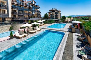 a swimming pool with chairs and umbrellas next to a building at Premier Luxury Mountain Resort in Bansko