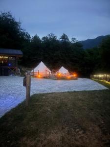a group of tents in a field at night at Vatra Bunătăților- By The Lake in Proeni