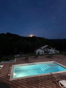 a swimming pool at night with a house in the background at Cabanutele M&V INFINIT in Sălătrucel