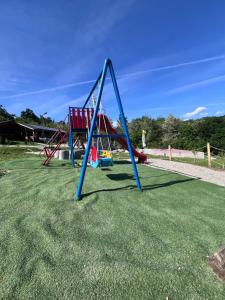 a playground with two swings on the grass at Cabanutele M&V INFINIT in Sălătrucel