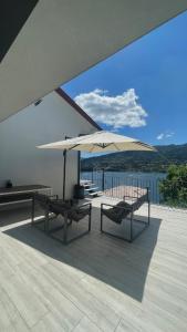a patio with two benches and an umbrella at Casa Miralago - Gerês in Admeus