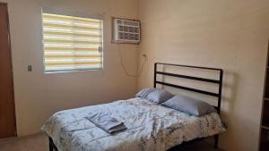 a bed in a room with a window and a pillow at Las Veredas Aeropuerto in San José del Cabo
