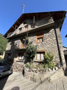 a stone building with a balcony on top of it at Casa Campaner in Valencia de Aneu
