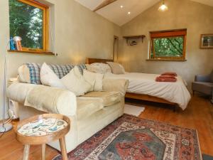 a living room with a couch and a bed at Brambly Cabin in Crediton