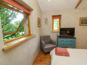 a bedroom with a bed and a chair and a window at Brambly Cabin in Crediton