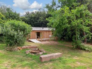a wooden cabin in a yard with a tree at Brambly Cabin in Crediton