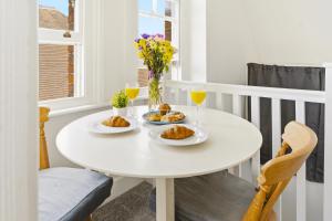 a white table with two plates of food and drinks at Sky View En-Suite in Egham